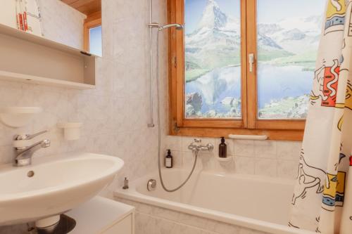 uma casa de banho com um lavatório, uma banheira e uma janela em Studio dans le plus beau village de Suisse em Grimentz