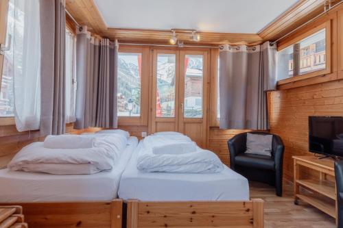 um quarto com 2 camas, uma televisão e uma cadeira em Studio dans le plus beau village de Suisse em Grimentz