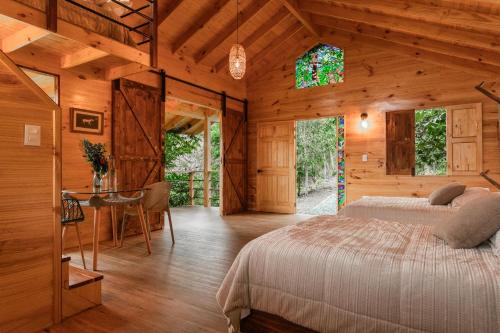 una camera da letto in una cabina di legno con un letto e un tavolo di Tominejo Ecolodge Casas en los árboles a Neira