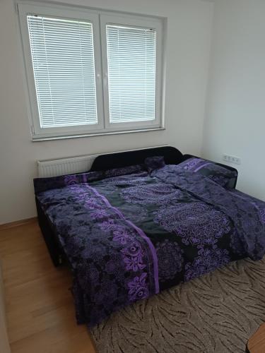 a bed with a purple comforter in a bedroom at 2BDR Apt with Balcony view - Free parking 2 in Sarajevo