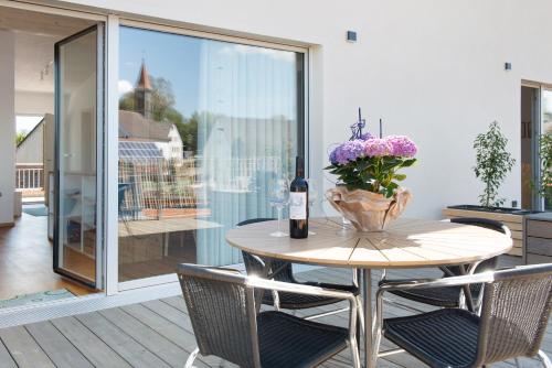 a table with a vase of flowers and a bottle of wine at Ferienwohnungen Walz in Pfullendorf