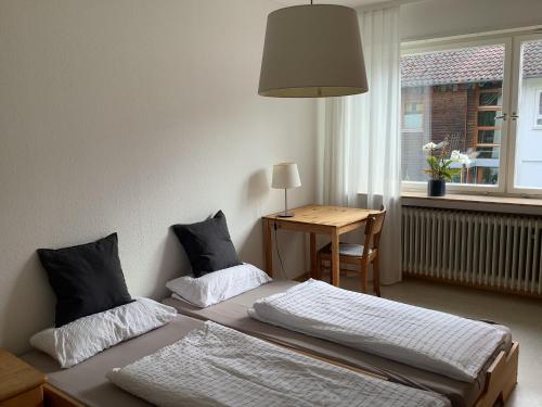テュービンゲンにあるFerienwohnung Kliniknähe mit Blick ins Grüneのベッド2台、テーブル、窓が備わる客室です。