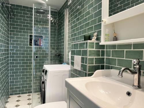 La salle de bains est pourvue d'un lavabo, de toilettes et de carrelage vert. dans l'établissement Lovely apartment with sea view on Hono, à Hönö