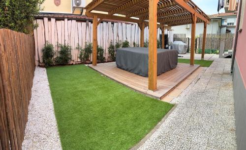 a garden with a table in a wooden pergola at Bilocale completamente rinnovato a 100 metri dal mare con giardino in Marina di Massa