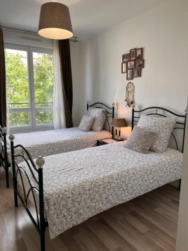 deux lits dans une chambre avec une fenêtre dans l'établissement Appt à 10 min de Paris, 15 min a pied du SDF, à Saint-Denis
