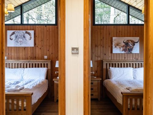 Luxury Cabin With Hot Tub and Sauna في أوتيربيرن: سريرين في غرفة بها نافذتين