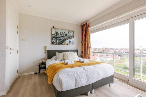 een slaapkamer met een bed en een groot raam bij Huswell - Apartment with lake view & common indoor pool in Knokke-Heist