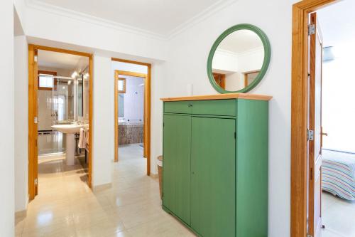 baño con armario verde y espejo en Sa Trona Beach House, en Cala Santanyi