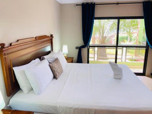 sypialnia z dużym białym łóżkiem i oknem w obiekcie Seafront Residences & Hotel w mieście Bijilo