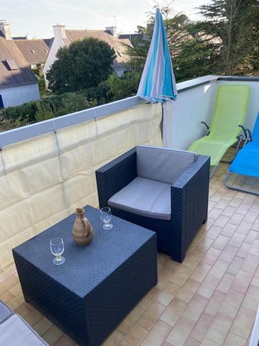 un patio avec une table, des chaises et un parasol dans l'établissement Appartement lumineux et au calme, 800 m de la plage, à Larmor-Plage