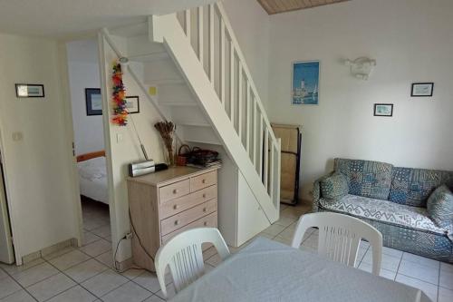 - un salon avec un escalier, une table et des chaises dans l'établissement La Grière résidence avec piscine, à La Tranche-sur-Mer