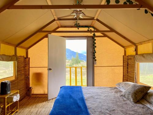 蘇埃斯卡的住宿－Coclí Glamping Suesca，一间卧室设有一张床和一个大窗户