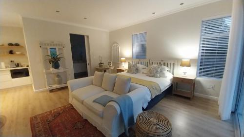 a bedroom with a white bed and a couch at Knysna Private Estate Lagoon Apartment - Garden Apartment - Secure Estate in Knysna