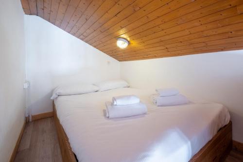 een slaapkamer met een bed met witte lakens en een houten plafond bij Skyhook: Batiment B in Chamonix-Mont-Blanc