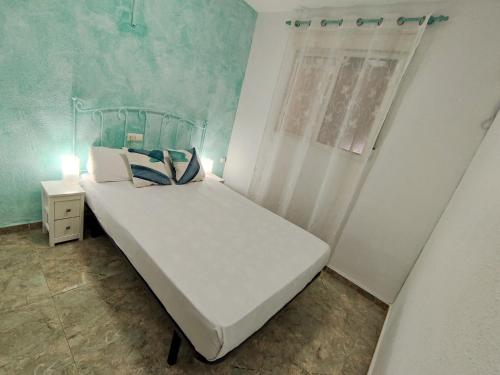 a small bedroom with a white bed and a window at Apartamento Gandia Bellreguard 3000 in Bellreguart