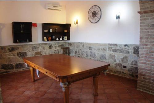 a wooden table in a room with a clock on the wall at VILLA CATERINA in Calasetta