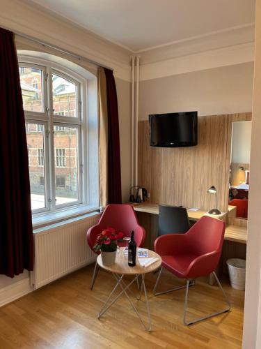 a living room with two red chairs and a table at Hotel Skandia in Helsingør