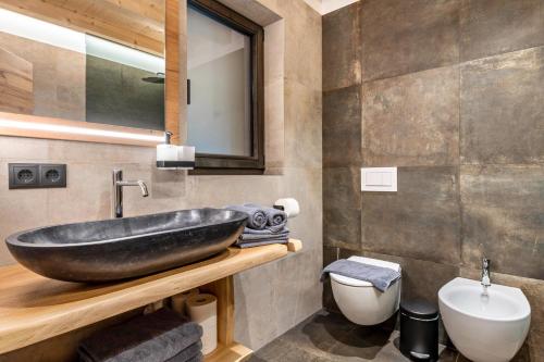 a bathroom with a black sink and a toilet at Blosegghof Bergchalets Waldblick in Racines