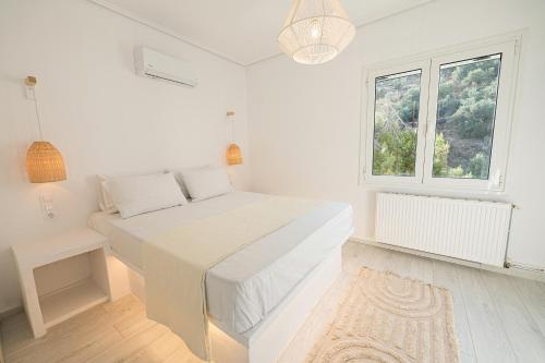 a white bedroom with a bed and a window at The White Rose Hotel in Poros