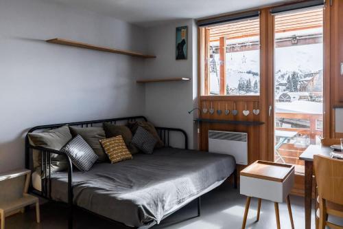 a bedroom with a bed and a table and a window at IMMODREAMS - La Tanière - Avoriaz in Avoriaz