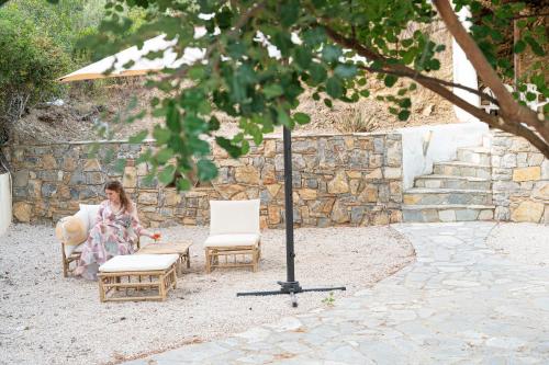 a woman sitting in a chair next to two chairs at The White Rose Hotel in Poros
