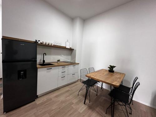 a kitchen with a table and a black refrigerator at Cactus Apartments in Durrës