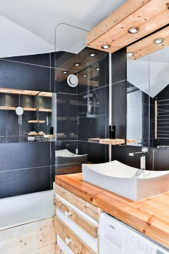 La salle de bains est pourvue de murs noirs et d'un lavabo blanc. dans l'établissement IMMODREAMS - Le Pas du Lac - Avoriaz, à Avoriaz