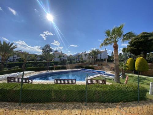 una piscina con 2 bancos y palmeras en Beautiful Apartment Alfaz del Sol en L’Alfàs del Pi
