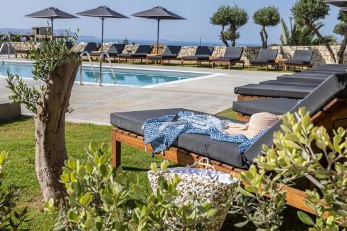 une femme assise sur une chaise longue à côté d'une piscine dans l'établissement Basilico Suites Adults Only, à Gouves