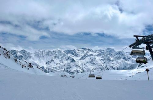 a ski lift with snow covered mountains in the background at Sporthotel Bergheim in Sölden