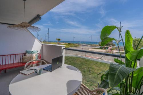 einen Balkon mit einem Tisch und einem Laptop darauf in der Unterkunft Heima in front of the Sea in Málaga