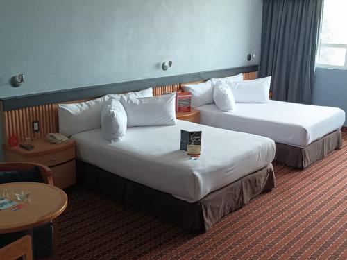 a hotel room with two beds and a table at Suites Inn la Muralla Hotel & Spa in Toluca