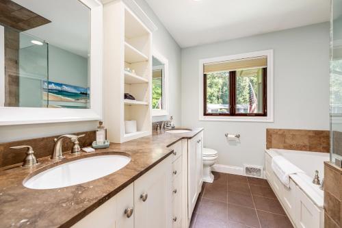 a bathroom with a sink and a tub and a toilet at The Milliken Getaway AC Beach Fire Pit BBQ in Traverse City