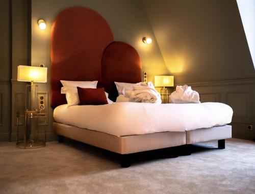 a bedroom with a large white bed with two lamps at Hôtel Château Héloïse in Mérélessart