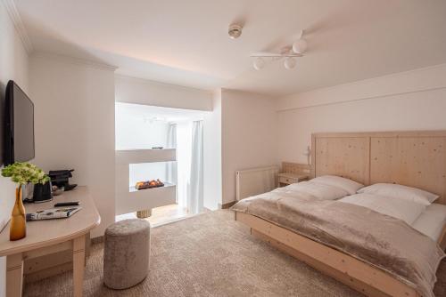 a bedroom with a bed and a desk and a television at das zellersee in Zell am See