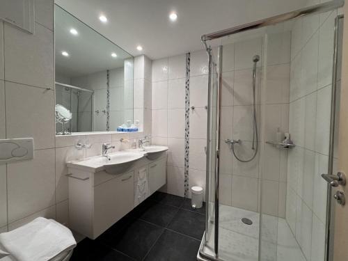 a white bathroom with a shower and a sink at Chalet Bella Vista 12 - Penthouse in Wengen
