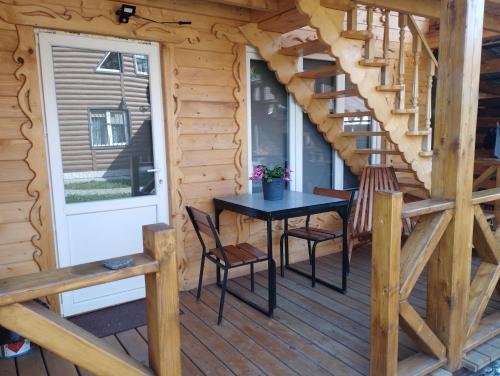 a wooden cabin with a table and chairs on a deck at Карпати котедж Анастасія in Skole