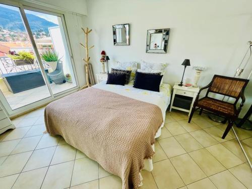 une chambre avec un lit, une chaise et une fenêtre dans l'établissement Le Victoria Beach, beau T2 à 1 minute des plages, à Menton