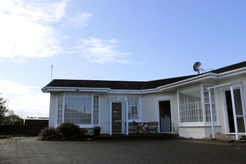 a white house with a table in front of it at Colonial Motel in Invercargill