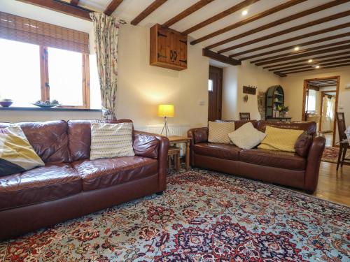 a living room with two leather couches and a rug at The Croft in Holsworthy