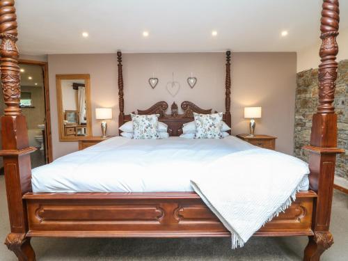 una camera da letto con un grande letto in legno con lenzuola bianche di The Croft a Holsworthy