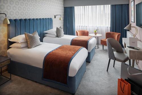 Queens Hotel & Spa Bournemouth في بورنموث: غرفة فندقية بسريرين وطاولة