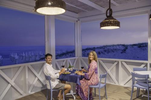 a man and woman sitting at a table in a restaurant at Riva di Ugento Beach Camping Resort in Ugento