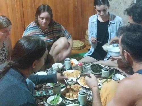Un gruppo di persone seduti intorno a un tavolo che mangiano cibo di Trieu Hoan homestay a Cao Bằng
