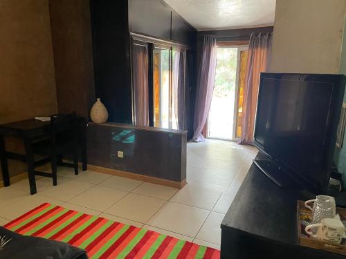 a living room with a flat screen tv and a table at Sergio chambre d hôte in Sali Nianiaral