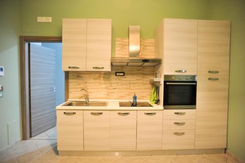 cocina con armarios de madera, fregadero y microondas en In Center apartaments, en Salerno