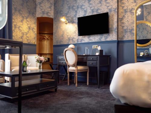 a bedroom with a bed and a desk and a television at Hôtel Château Héloïse in Mérélessart