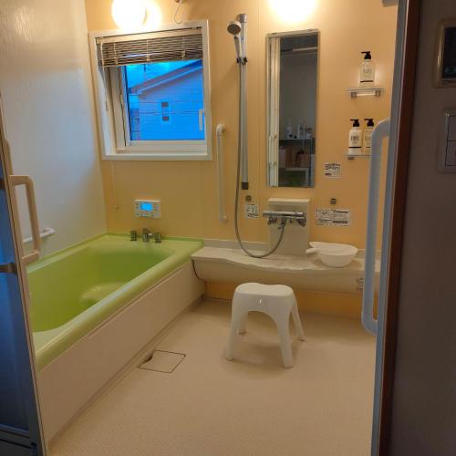 a bathroom with a green tub and a toilet and a sink at Hokkaido Hakodate Onuma National Park Kenzo's House in Ōnuma