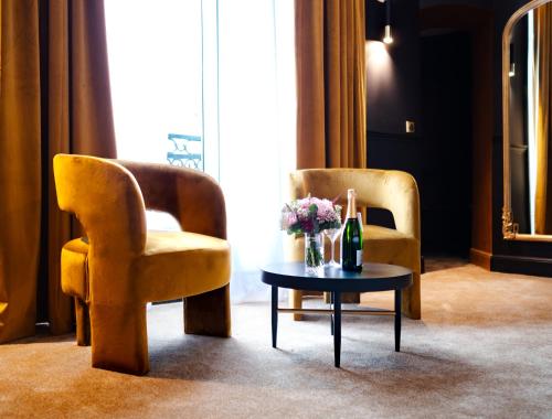 two chairs and a table with a bottle of champagne at Hôtel Château Héloïse in Mérélessart
