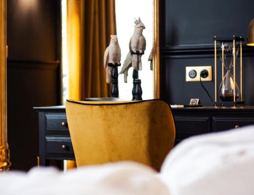 a chair in a bedroom with a table and a mirror at Hôtel Château Héloïse in Mérélessart